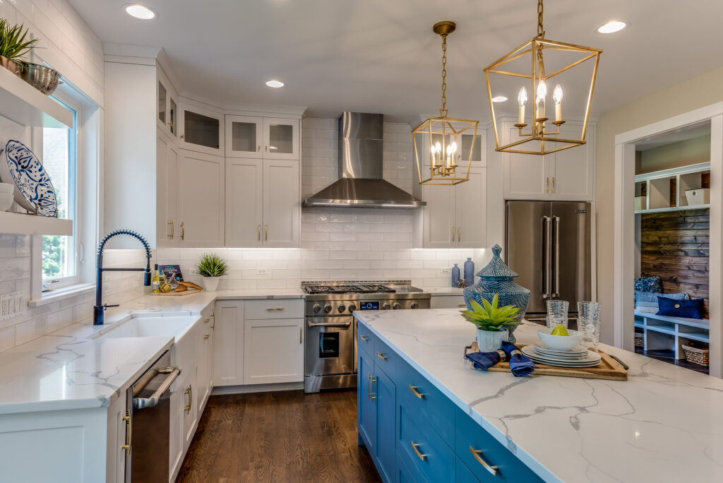 Calabasas kitchen remodel: Bright kitchen with white shaker cabinets, blue island, quartz countertops, and gold lantern pendants in Calabasas by RnD Builders Inc