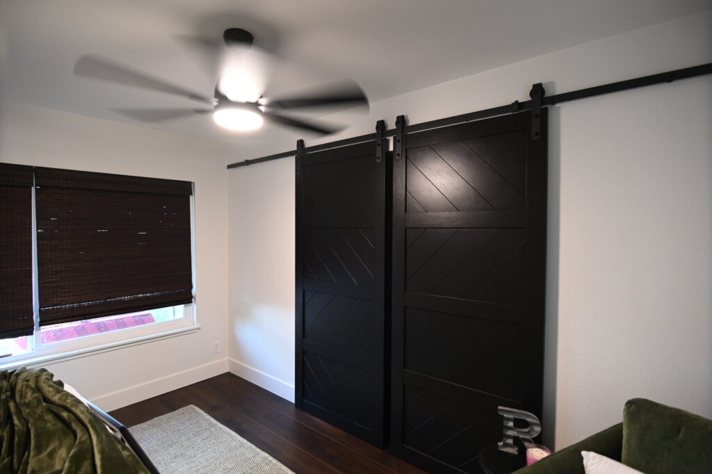 Simi Valley home remodel: Bedroom with double black sliding barn doors on matte black hardware rail in Simi Valley by RnD Builders Inc