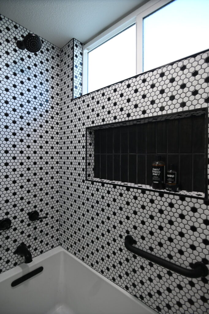 Black and white hexagon mosaic tile shower with built-in niche and matte black fixtures by RnD Builders Inc