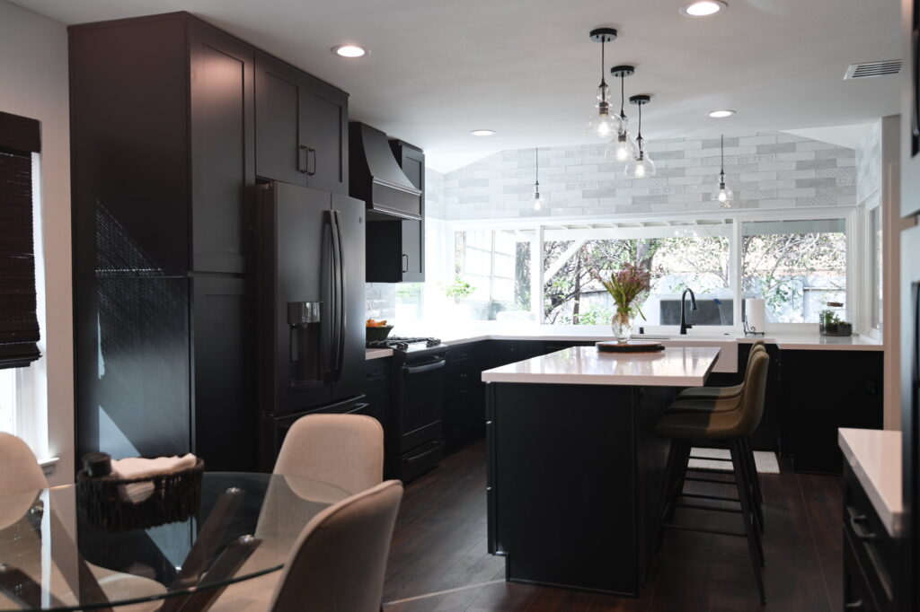 Dark shaker cabinet kitchen with white quartz island, black appliances, and pendant lighting by RnD Builders Inc