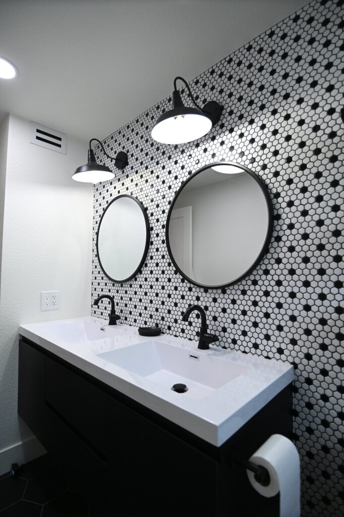 Simi Valley Home Remodel Modern black and white bathroom with hexagon tile accent wall, dual round mirrors, and floating vanity by RnD Builders Inc