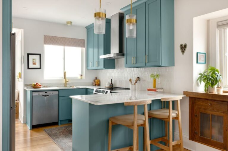 Teal shaker-style kitchen with white quartz island, brass hardware, and pendant lights by RnD Builders Inc