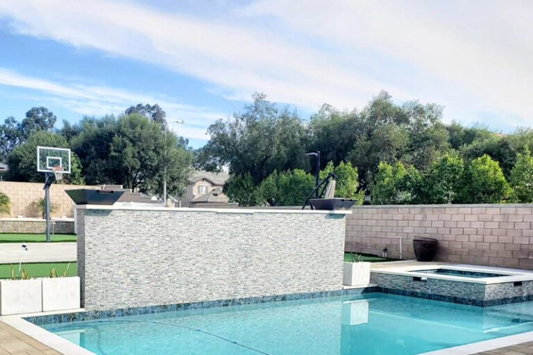 Backyard Pool with Stacked Stone Water Feature Wall Backyard pool with stacked stone water feature wall, spa, and basketball court by RnD Builders Inc