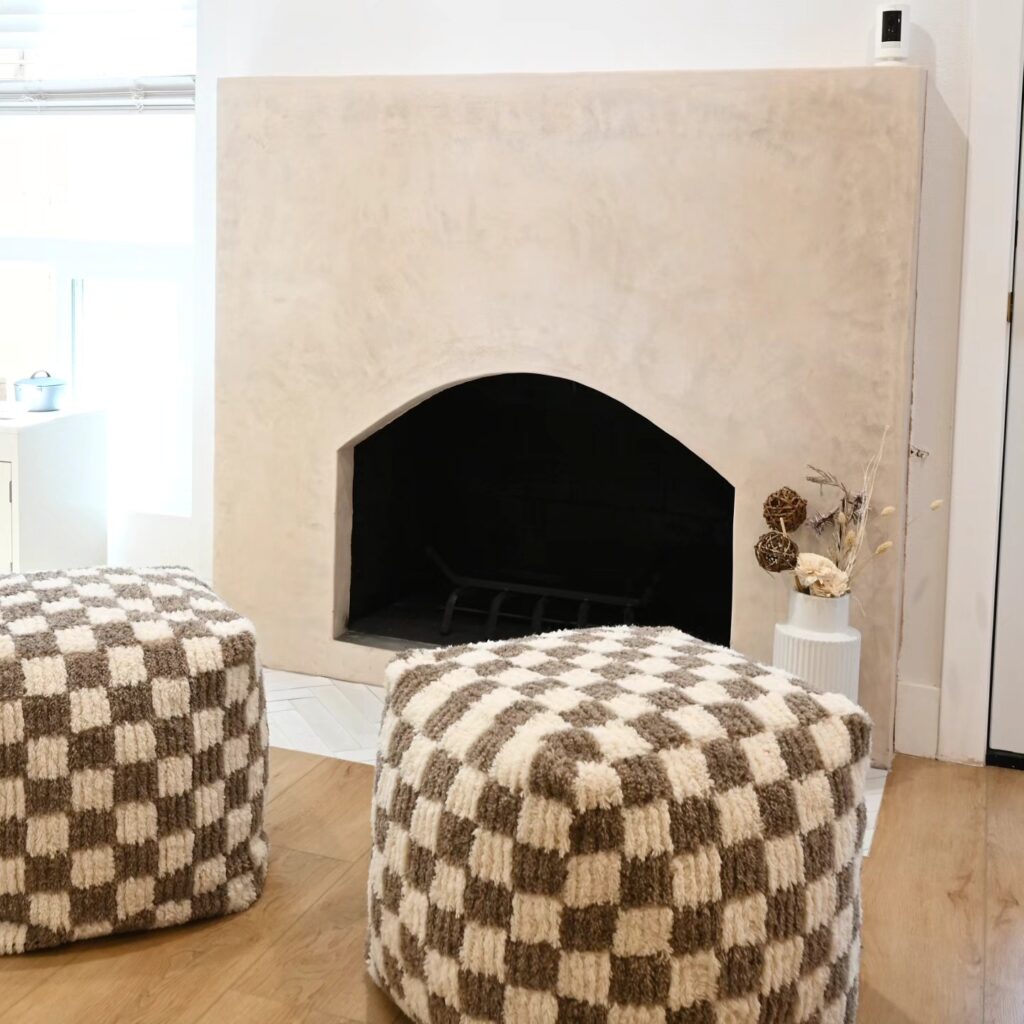 Plaster-finish Arched Fireplace Surround Plaster-finish arched fireplace surround with hardwood floors and checkered ottomans by RnD Builders Inc