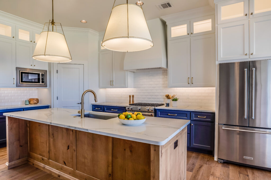 Transitional kitchen with navy lower cabinets, knotty alder island, quartz countertops, and drum pendant lights in Westlake Village by RnD Builders Inc