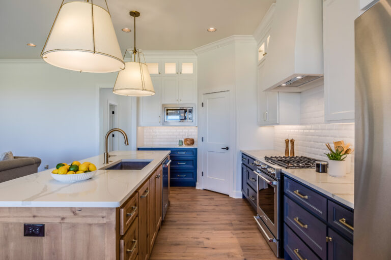Transitional kitchen with navy blue lower cabinets, natural wood island, quartz countertops, and brass pendants in Westlake Village by RnD Builders Inc