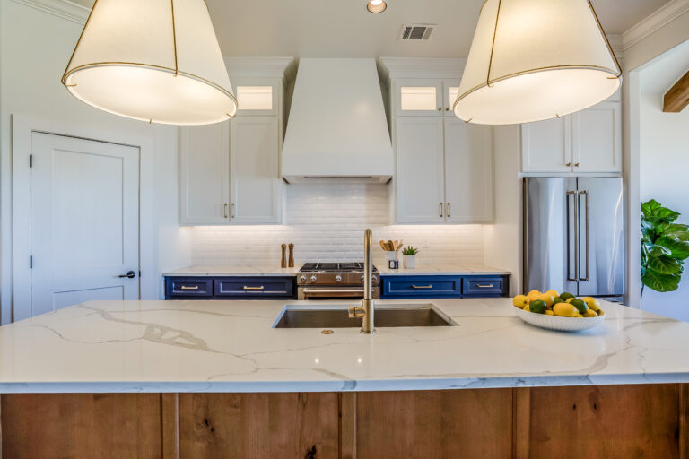 White and navy kitchen with quartz island, custom hood, and stainless appliances in Westlake Village by RnD Builders Inc
