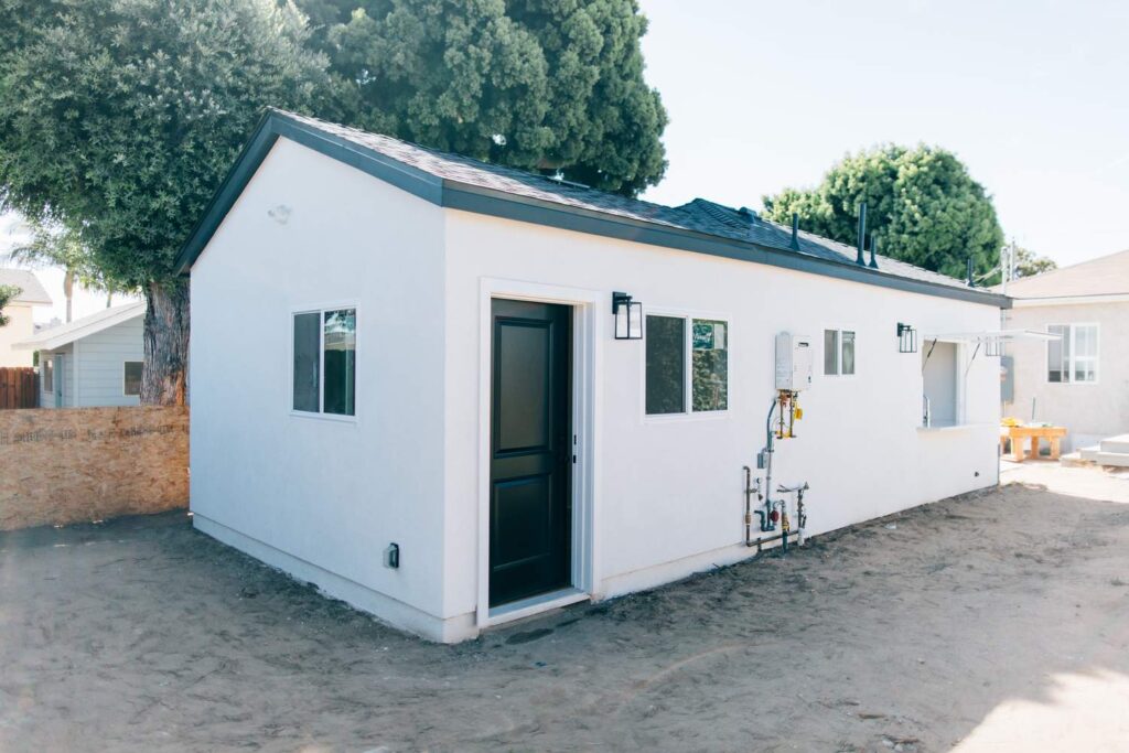 Newly Built White Stucco ADU with Pitched Roof in Hawthorne Newly built white stucco ADU with pitched roof, black entry door, and solar panels in Hawthorne by RnD Builders Inc