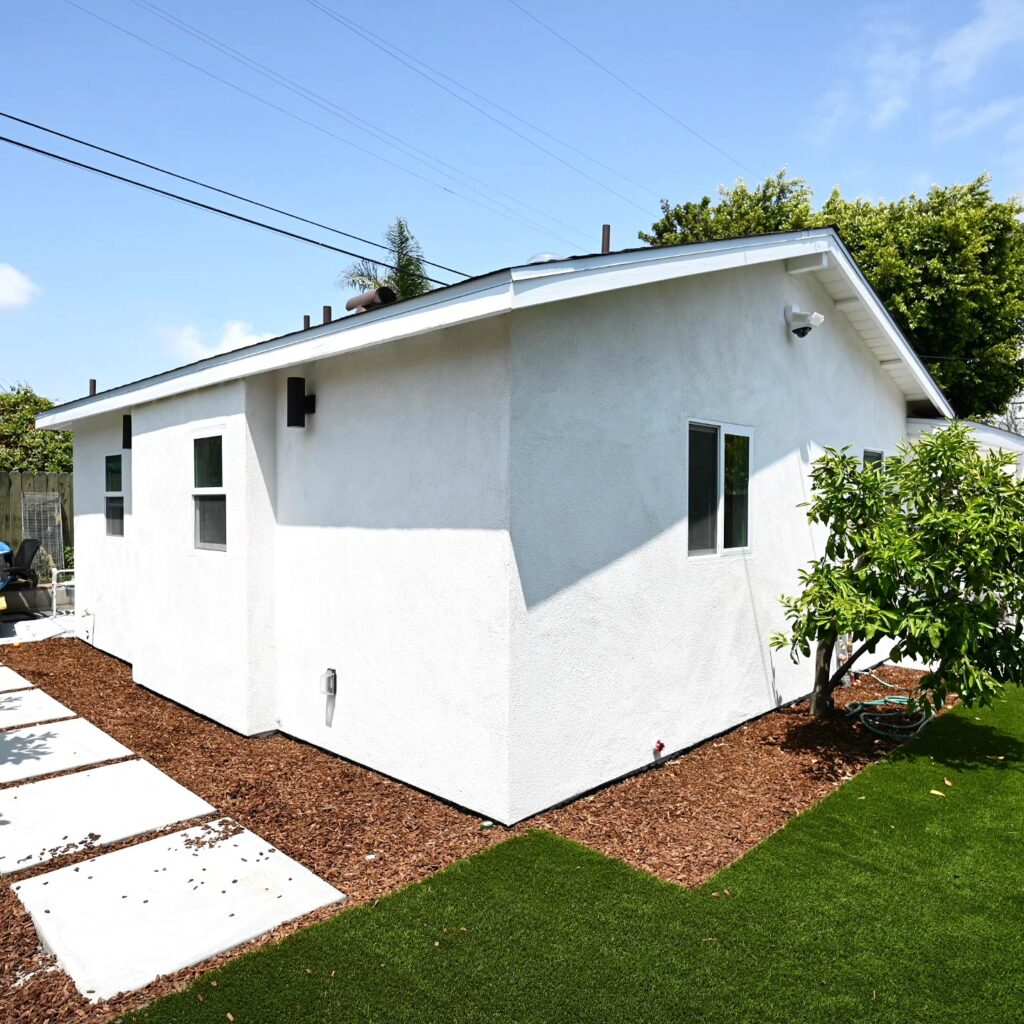 White Stucco ADU Exterior with Gable Roof White stucco ADU exterior with gable roof, concrete pavers, and artificial turf landscaping by RnD Builders Inc