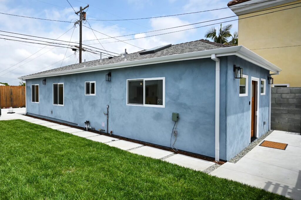 Newly Built ADU with Blue-gray Stucco Newly built ADU with blue-gray stucco exterior, white trim windows, and asphalt shingle roof by RnD Builders Inc