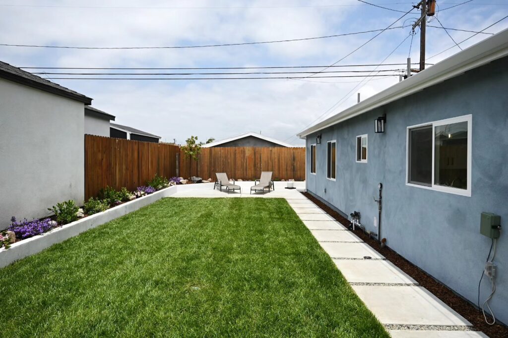 Landscaped Backyard with Green Lawn Ground cover contractor project: landscaped backyard with a green lawn, concrete stepping stones and planter borders by RnD Builders