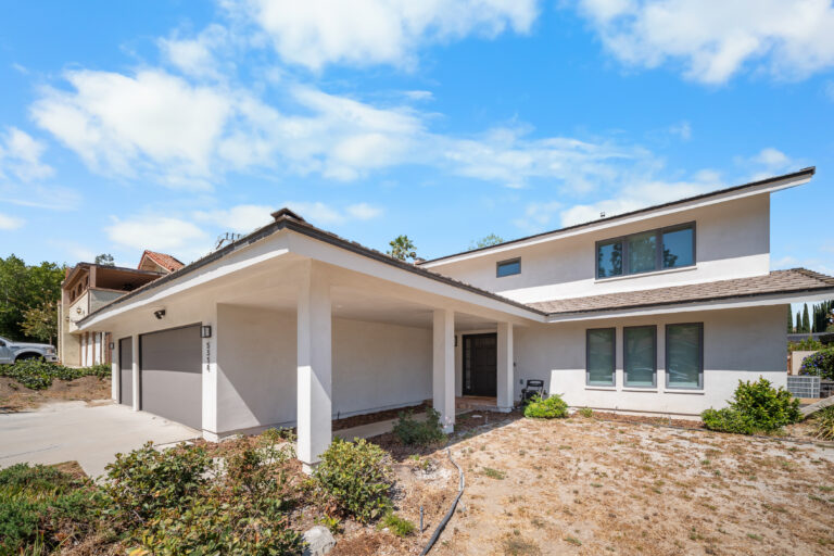 Two-story stucco home with attached garage, covered entry, and large windows by RnD Builders Inc