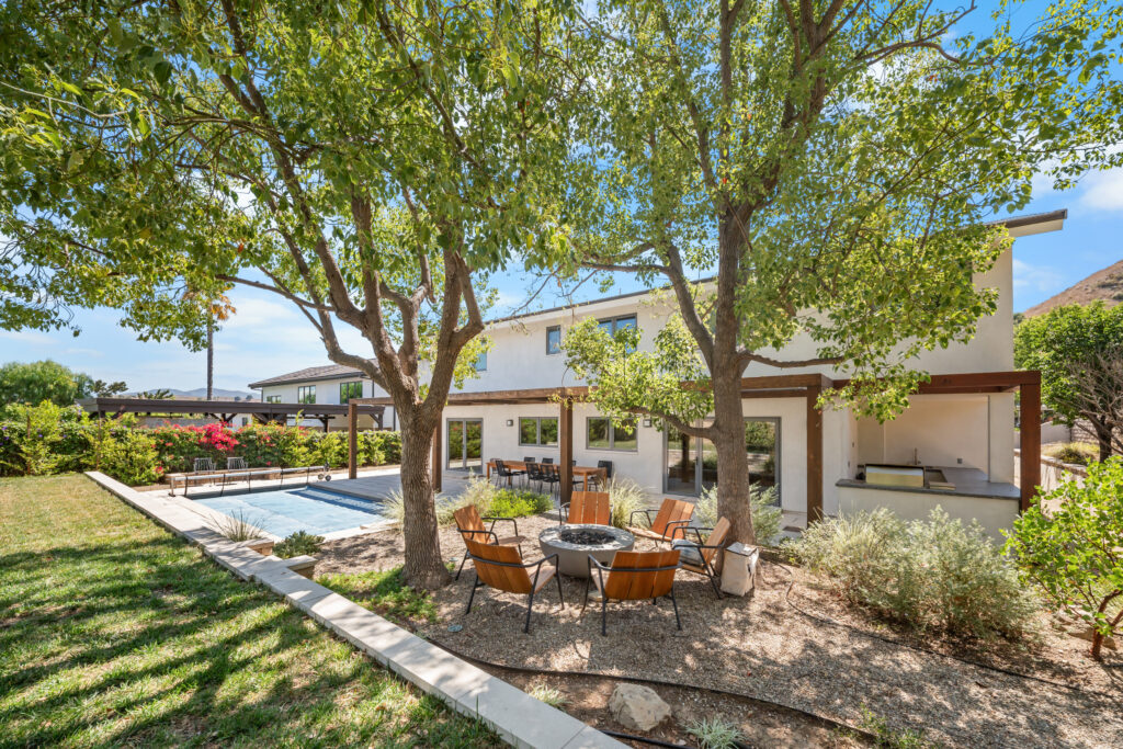 Modern two-story white stucco home with backyard fire pit, pool, and wood pergola by RnD Builders Inc
