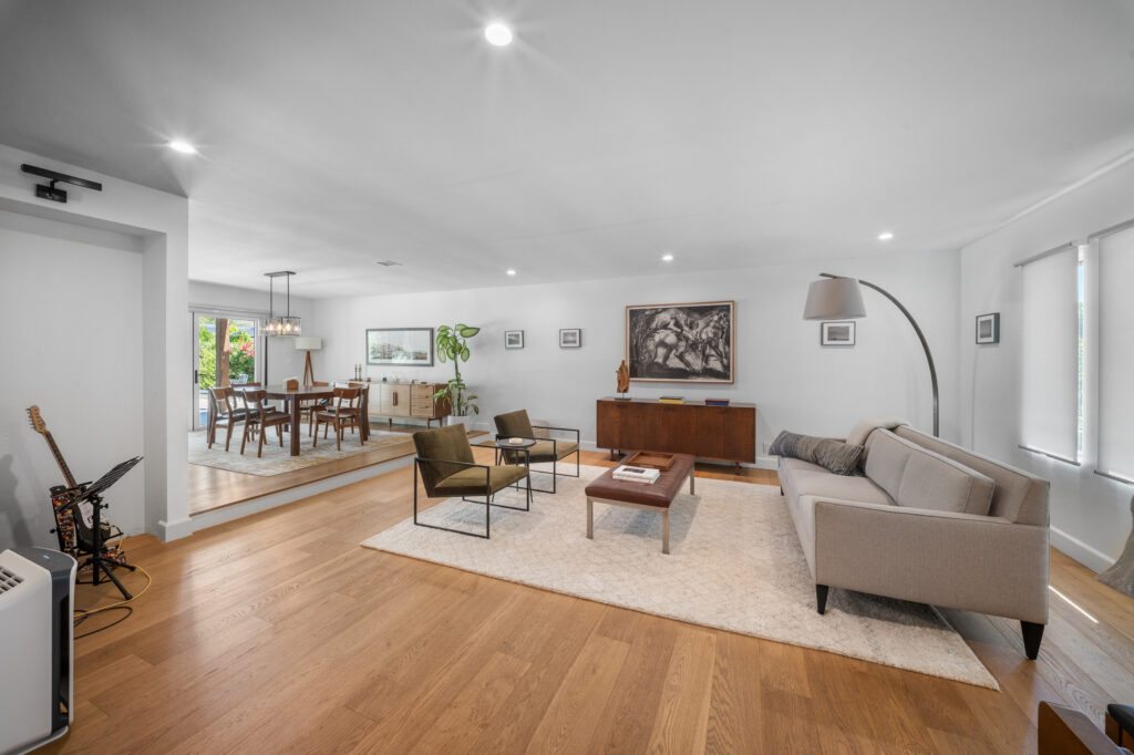 Open-concept mid-century modern living and dining room with wide-plank hardwood floors by RnD Builders Inc