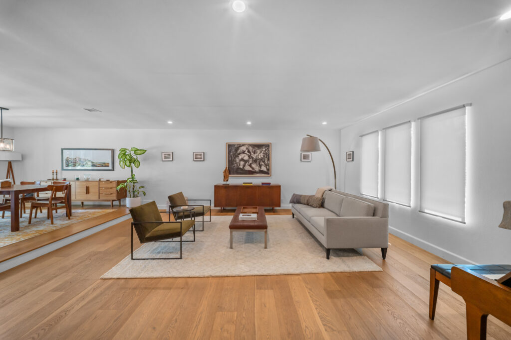 Open-concept mid-century modern living and dining room with wide-plank hardwood floors by RnD Builders Inc