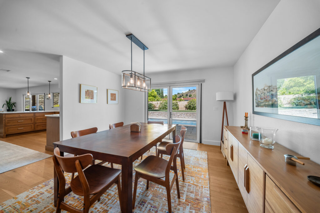 Open-plan dining room with walnut table, mid-century chairs, and hardwood floors by RnD Builders Inc