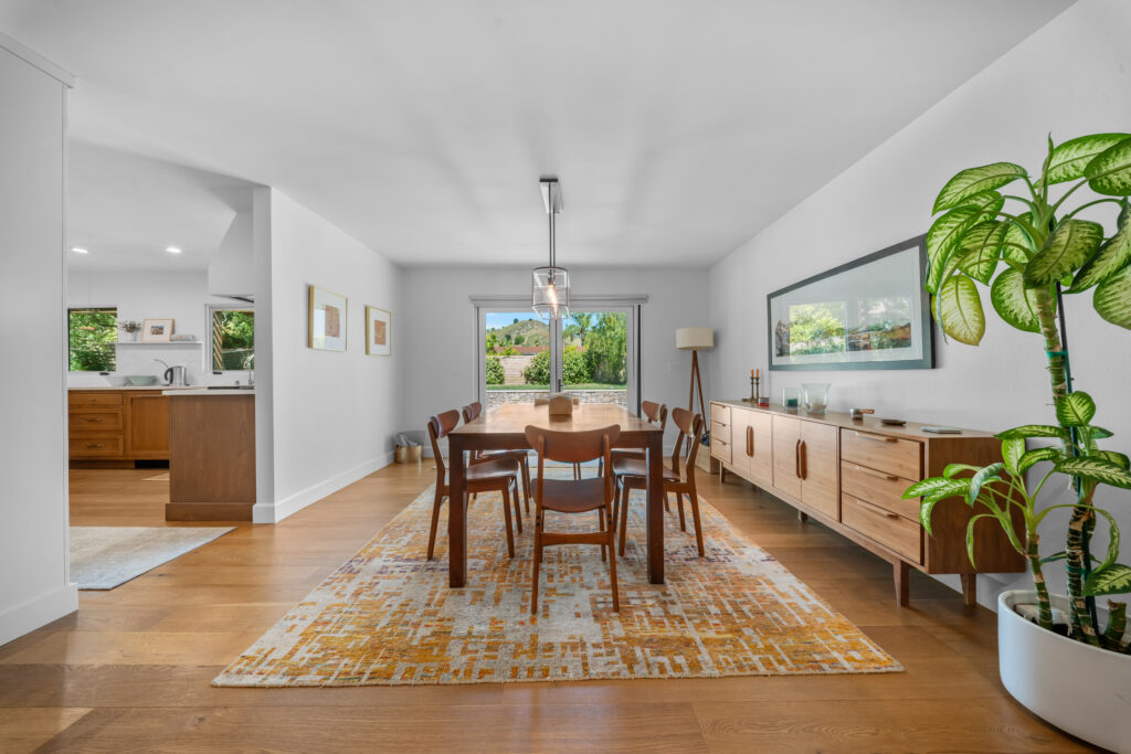 Mid-century modern dining room with hardwood floors, walnut table, and sliding glass door by RnD Builders Inc