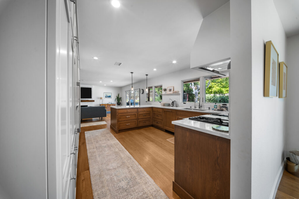 Open-concept kitchen with warm walnut cabinets, white quartz countertops, and hardwood floors by RnD Builders Inc