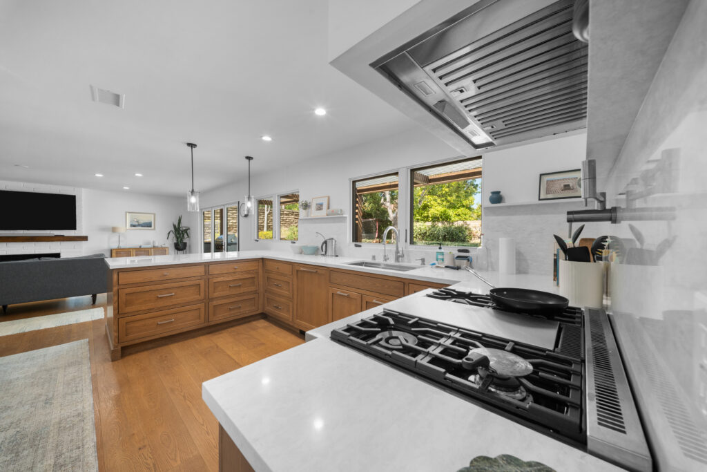 Open-concept kitchen with warm wood shaker cabinets, white quartz countertops, and stainless steel range hood by RnD Builders Inc