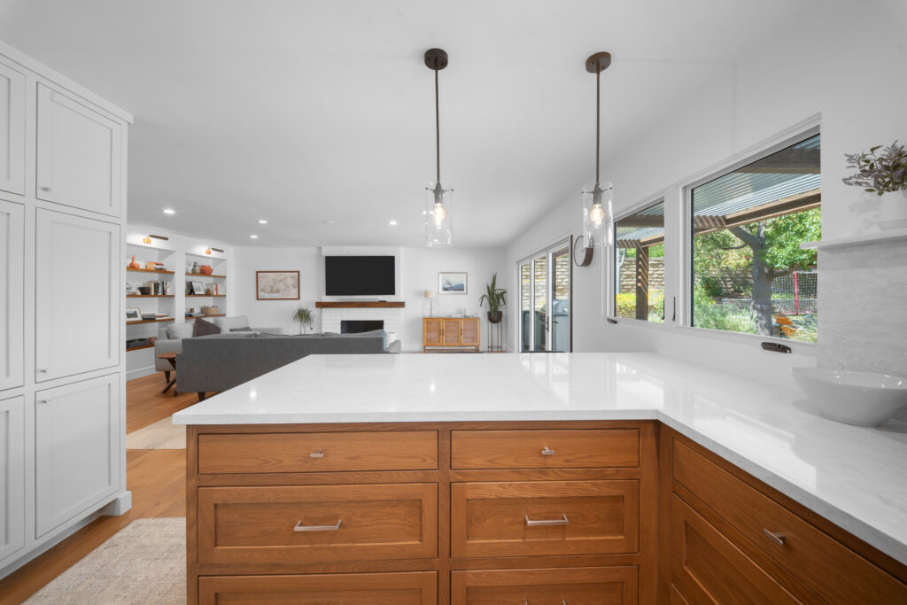 Open-concept kitchen with warm oak island, white quartz countertops, and glass pendant lights by RnD Builders Inc