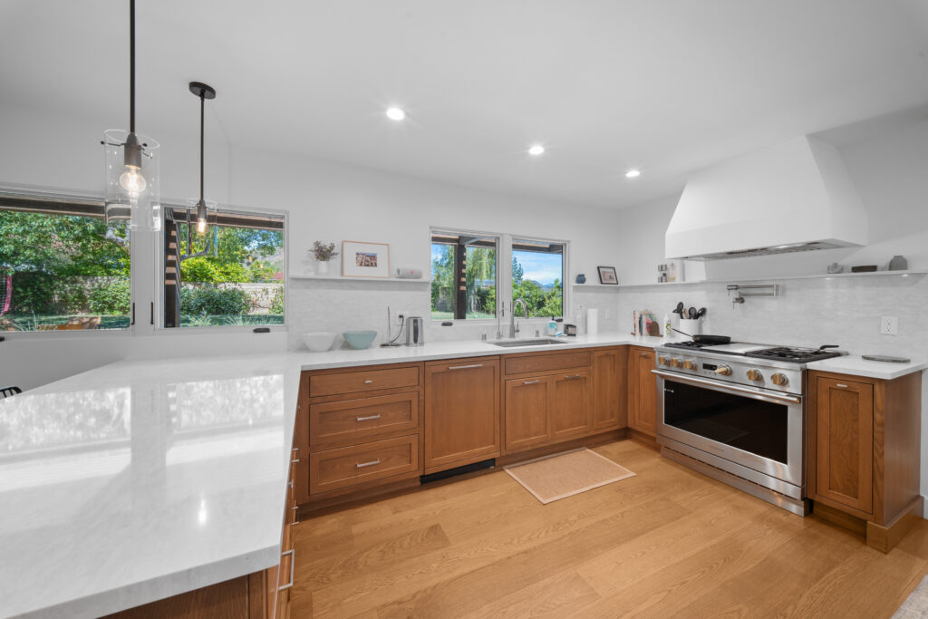 Bright kitchen with warm wood shaker cabinets, white quartz countertops, and stainless pro range by RnD Builders Inc