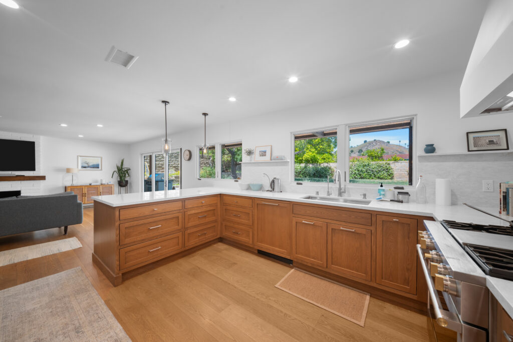 Open-concept kitchen with warm wood shaker cabinets, white quartz countertops, and L-shaped peninsula by RnD Builders Inc