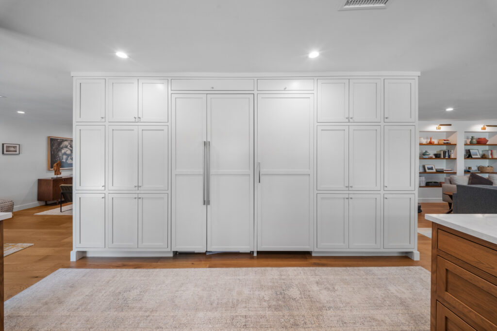 Floor-to-ceiling white shaker cabinetry with integrated panel-ready refrigerators and stainless bar pulls by RnD Builders Inc
