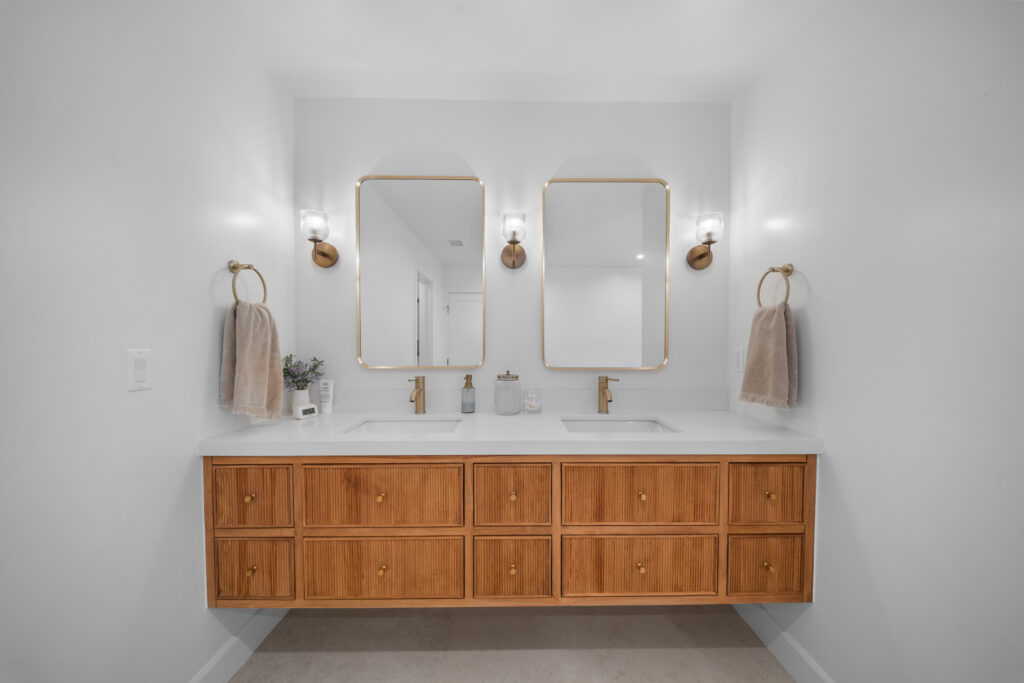 Floating double vanity with fluted wood drawers, white quartz countertop, and brushed gold fixtures by RnD Builders Inc