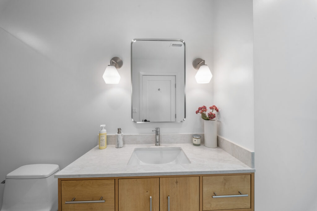 Modern bathroom vanity with natural wood cabinet, quartz countertop, and brushed nickel fixtures by RnD Builders Inc