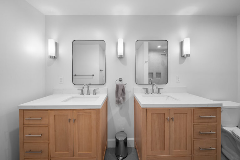 Dual vanity bathroom with natural wood shaker cabinets, white quartz countertops, and brushed nickel fixtures by RnD Builders Inc