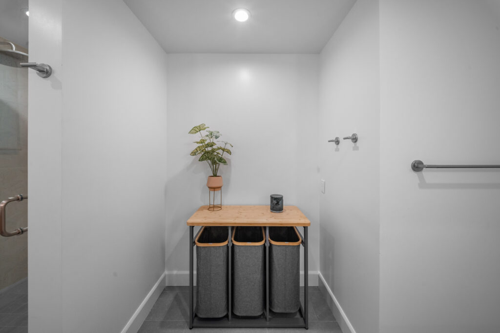 Clean white laundry or utility room with triple laundry sorter and bamboo countertop by RnD Builders Inc