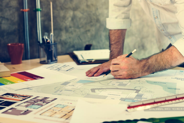 Design Studio Architect Creative Occupation Blueprint Concept Construction professional reviewing architectural floor plan blueprints with color swatches and pencil by RnD Builders Inc