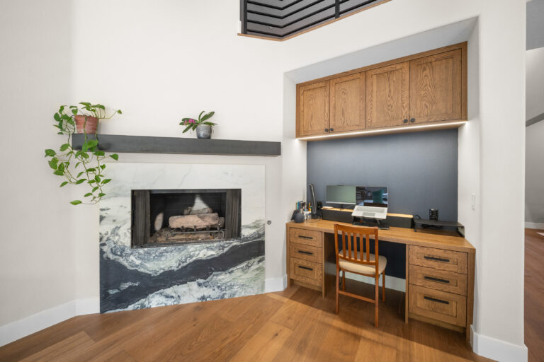 Open living space with marble fireplace surround and built-in oak home office nook by RnD Builders Inc