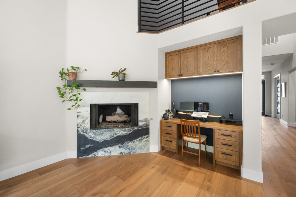 Open living area with marble fireplace surround and built-in oak home office nook by RnD Builders Inc