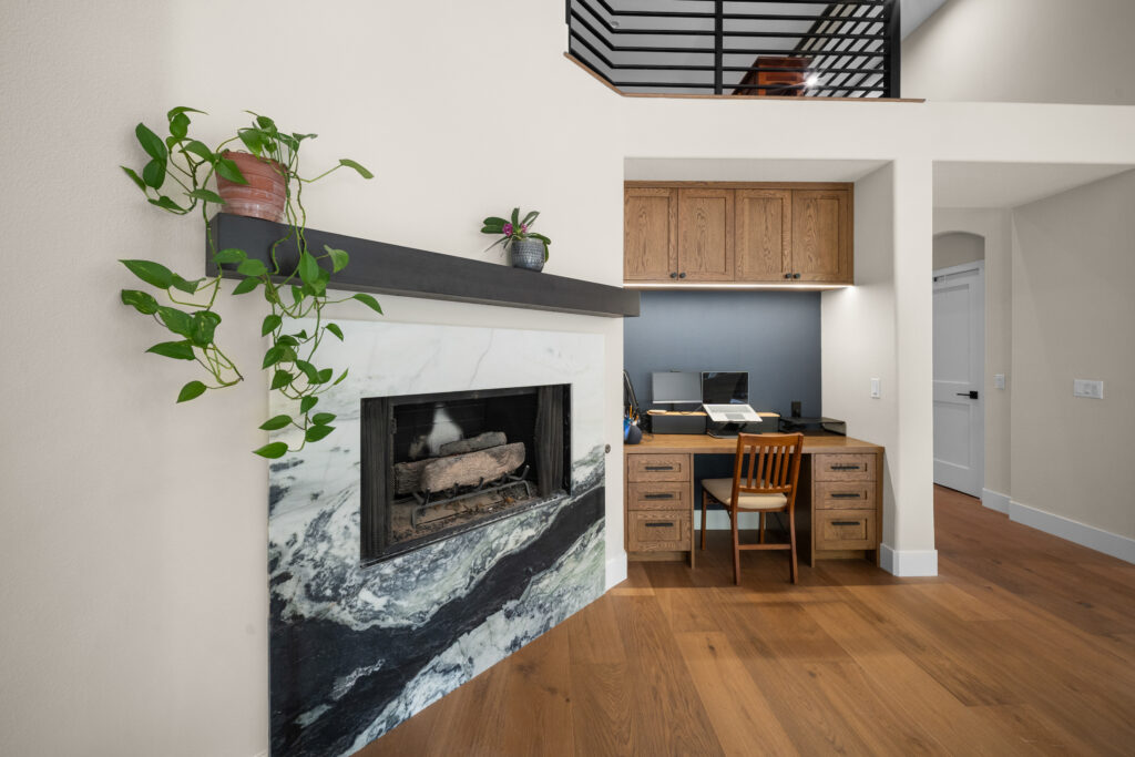Open living area with marble fireplace surround and built-in oak home office niche by RnD Builders Inc