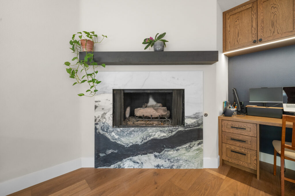 Marble-surround fireplace with dark floating mantel and built-in oak home office cabinetry by RnD Builders Inc