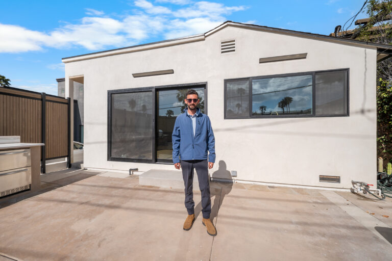 Roi Dahan of RnD Builders Inc standing in front of a white ADU with black-framed windows