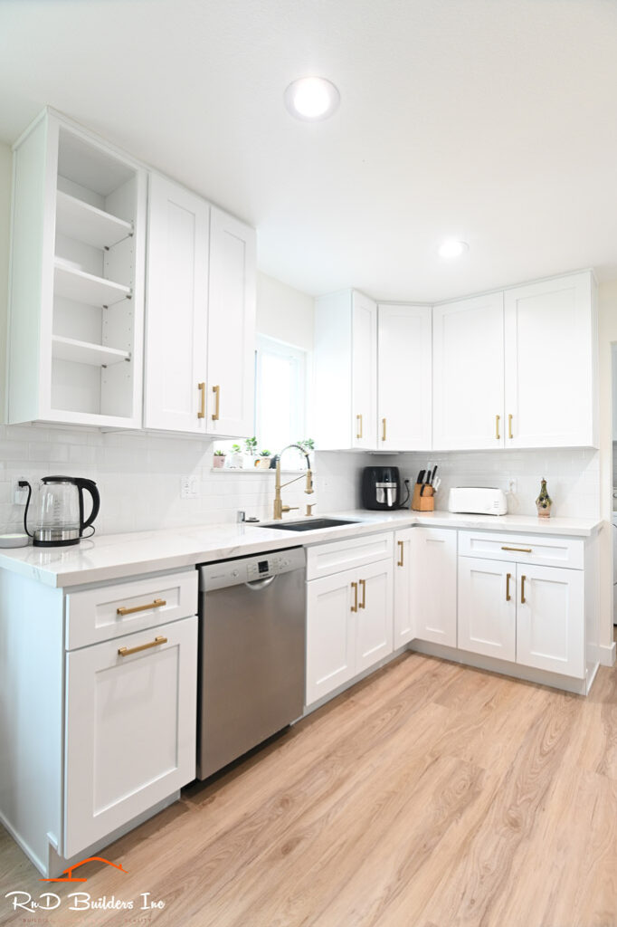 Thousand Oaks kitchen laundry: Bright white shaker cabinet kitchen with gold hardware and stainless steel dishwasher in Thousand Oaks by RnD Builders Inc