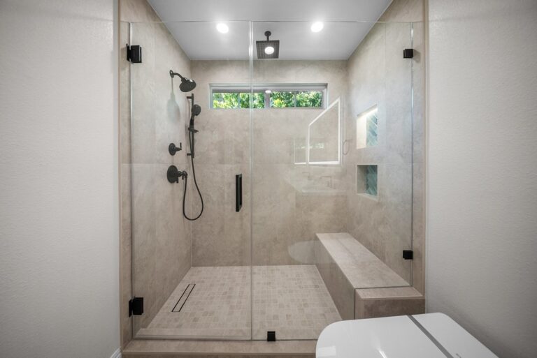 Agoura Hills bathroom remodel: Large walk-in shower with frameless glass enclosure, matte black fixtures, and built-in bench in Agoura Hills by RnD Builders Inc