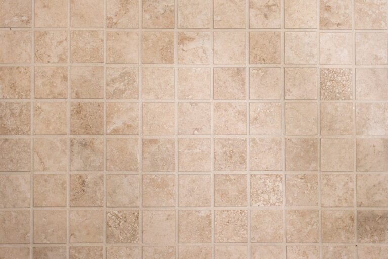 Close-up of beige travertine square tiles in grid pattern with matching grout by RnD Builders Inc