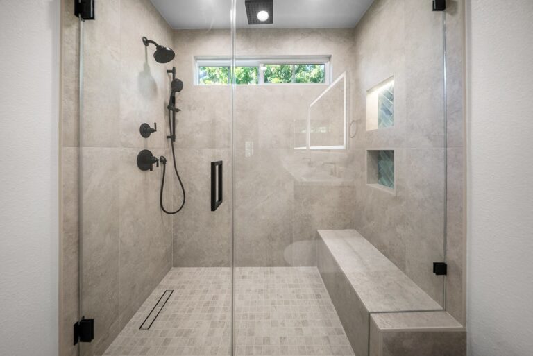 Agoura Hills bathroom remodel: Large walk-in shower with gray large-format tile, built-in bench, and matte black fixtures in Agoura Hills by RnD Builders Inc