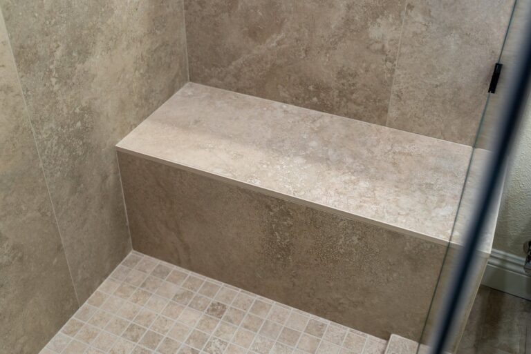 Tiled shower bench with large-format stone-look porcelain walls and mosaic floor by RnD Builders Inc