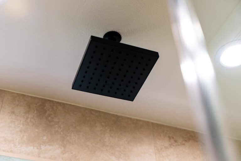 Agoura Hills bathroom remodel: Matte black square ceiling-mount rain shower head above beige tile shower walls in Agoura Hills by RnD Builders Inc