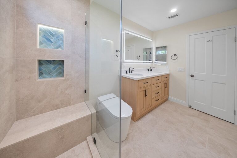 Agoura Hills bathroom remodel: Modern master bathroom with walk-in glass shower, blue herringbone tile niches, and oak double vanity in Agoura Hills by RnD Builders Inc
