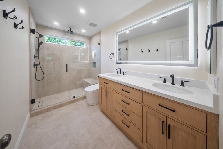 Agoura Hills bathroom remodel: Modern master bathroom with dual-sink wood vanity, LED mirror, and glass walk-in shower in Agoura Hills by RnD Builders Inc
