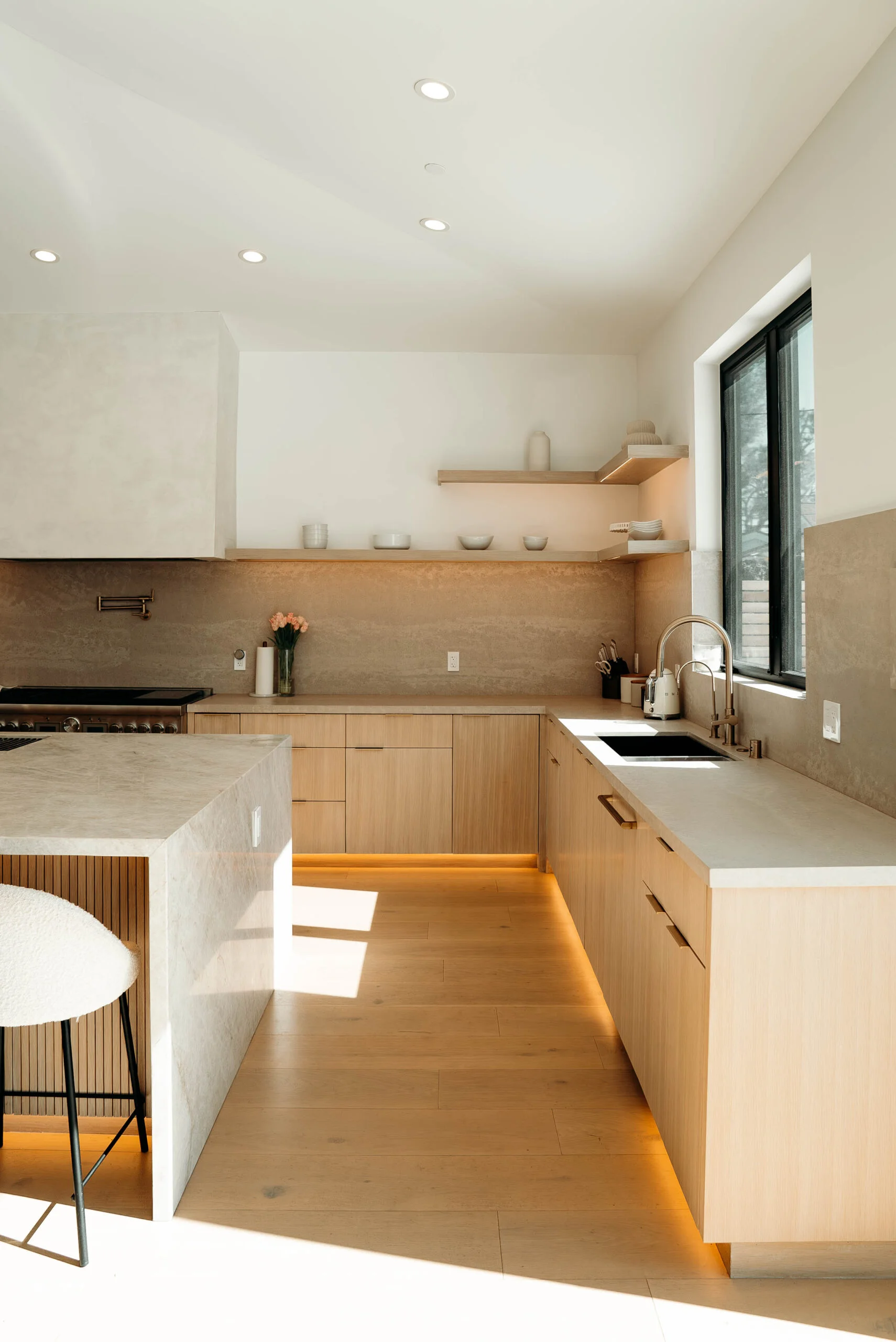 Minimalist kitchen with flat-panel oak cabinets, stone backsplash, and LED toe-kick lighting by RnD Builders Inc