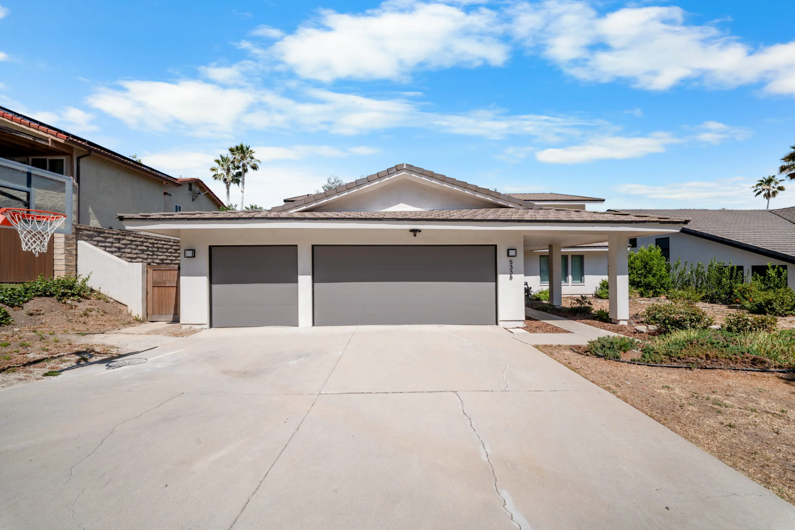 Single-story white stucco home with three-car garage and concrete driveway by RnD Builders Inc