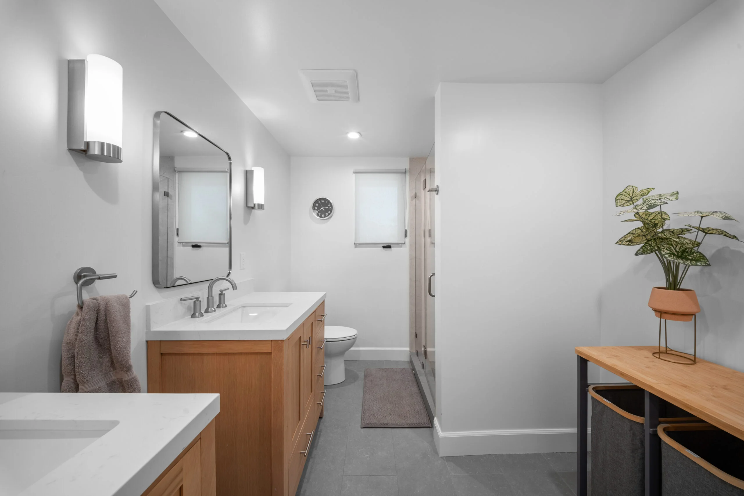 Modern full bathroom with warm wood vanity, white quartz countertop, and walk-in shower by RnD Builders Inc