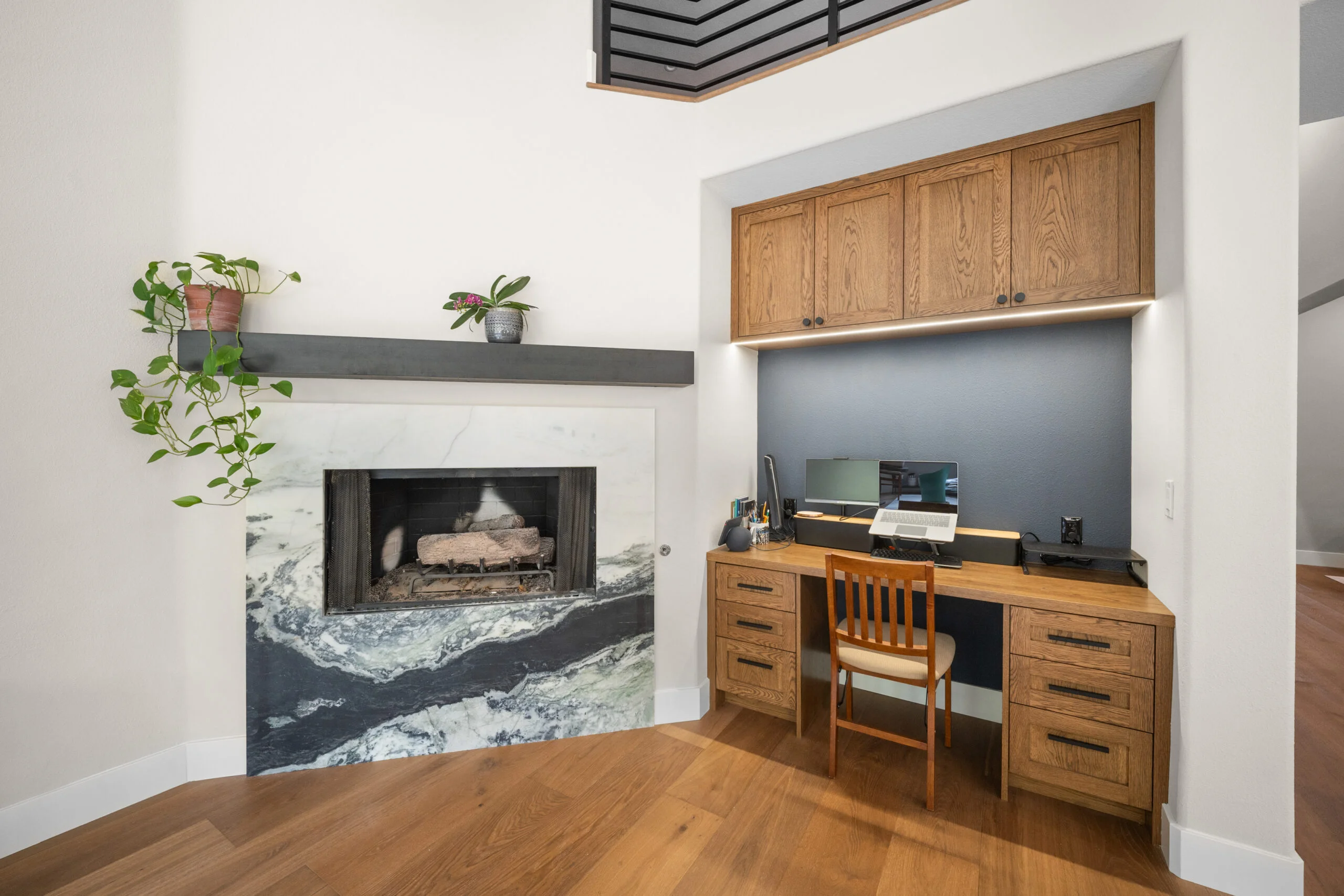 Open living space with marble fireplace surround and built-in oak home office nook by RnD Builders Inc
