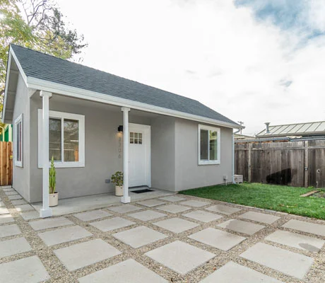 Newly built gray stucco ADU with gable roof and concrete paver patio by RnD Builders Inc